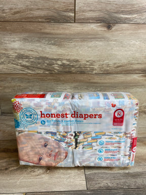 Front view of Honest Diapers size N 40 count sealed package showing colorful print and eco-friendly label on wood floor