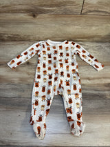 Baby footed sleeper with brown and orange reindeer print on wooden floor