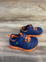 Side view of Stride Rite Phibian sneakers with navy perforated upper, orange sole, Velcro strap on wood background