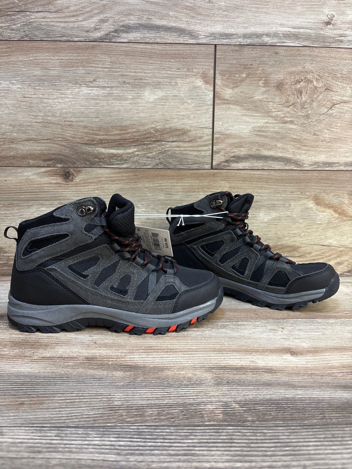 Pair of black and gray children’s hiking boots with red accents on wooden background
