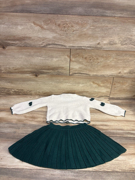 Front view of Haute Hippie 2pc knit cardigan and skirt set showing ivory cardigan with dark trim and pleated dark skirt on wood flooring