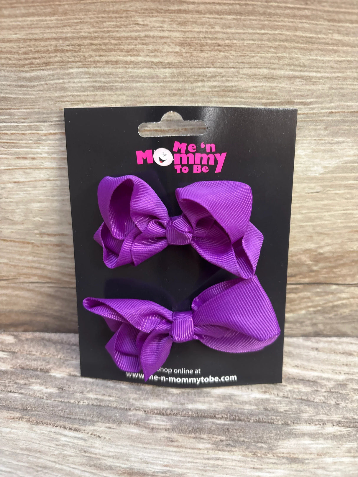Front view of 2 purple grosgrain ribbon hair bows on black display card with Me n Mommy To Be logo and wood background