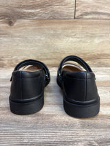 Rear view of black children's dress shoes with velcro straps on wooden floor