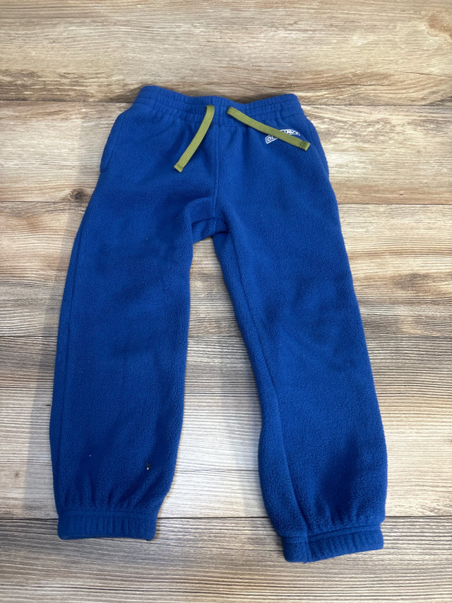 Blue fleece toddler pants with green drawstring on wood background