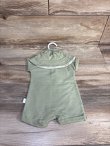 Flat lay of green Henley shortie romper and matching hat on hanger showcasing Henley buttons and cuffed legs on wood background