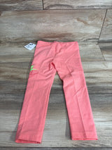 Flat lay of pink toddler Nike leggings showcasing neon green and red Nike logo on left leg with wood floor background