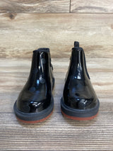 Black kids' ankle boots with polka dot pattern and brown soles on wood floor