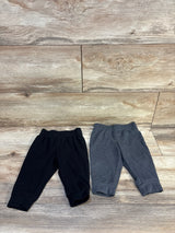 Black and gray baby jogger pants for infants, soft cotton blend with elastic waist and cuffs, laid flat on wood floor.