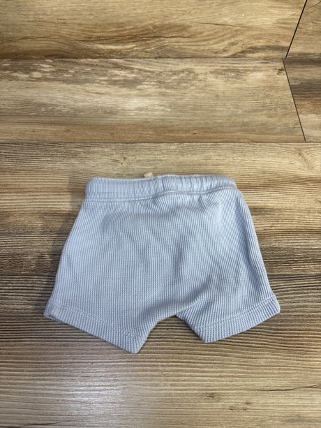 Top view of newborn blue Old Navy waffle knit pull on shorts showing ribbed texture and elastic waistband on wood background