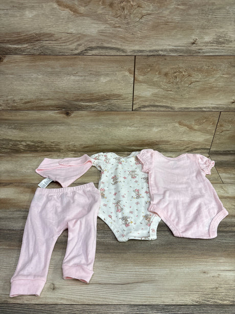 Four-piece Disney Baby Minnie Mouse layette set with pink bib, pants, bodysuit, and patterned onesie on wood