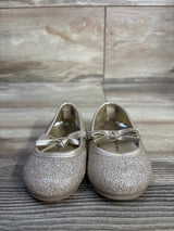 Front view of Koala Kids glitter bow ballet flats showing gold glitter finish and ribbon bows on a wood plank floor background