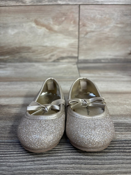 Front view of Koala Kids glitter bow ballet flats showing gold glitter finish and ribbon bows on a wood plank floor background