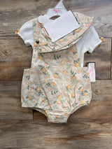 Front view of Little Lass 2-piece: white ribbed shirt with peach floral shortalls and hat on hanger over wood