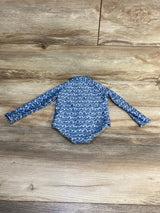 Blue baby rash guard with white wave pattern, long sleeves for sun protection on wood floor