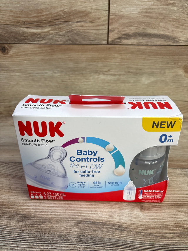 Front of NUK Smooth Flow 3-pack 5 oz anti-colic baby bottles in box showing Baby Controls the FLOW on packaging with wood surface background