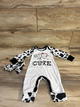 Flat lay white coverall with cow-print sleeves and matching headband, cow graphic reading HOLY IM CUTE, snaps