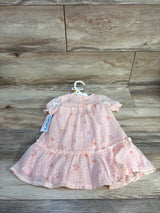 Front view of pink floral baby dress and matching bloomers on hanger showing ruffled hem and puff sleeves on wood background