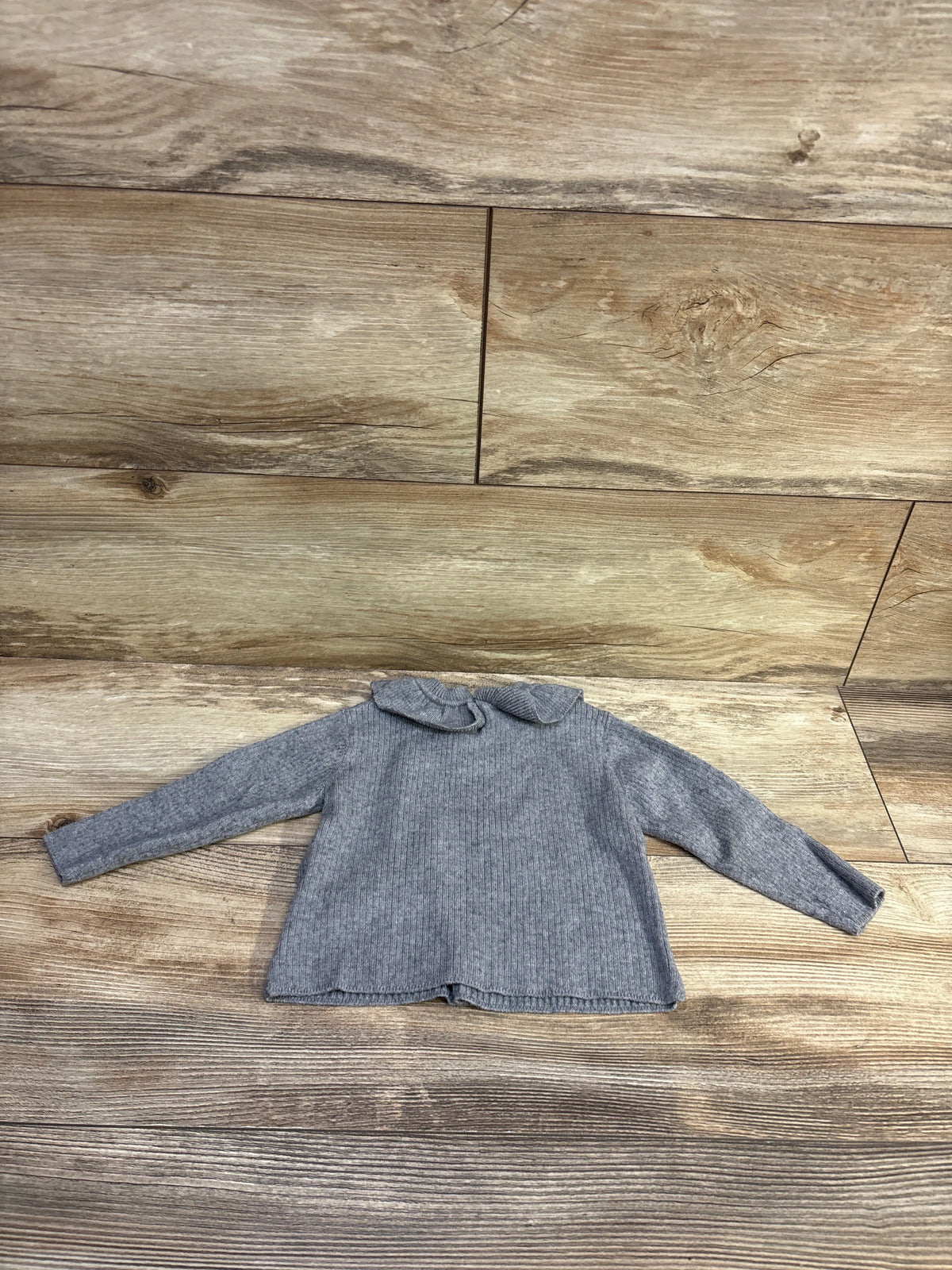 Front view of Zara grey ruffle collar sweater, size 6 to 9 months, with long sleeves and ribbed knit on wood