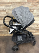 Gray Graco baby stroller with canopy, cup holder, and storage basket on wood floor