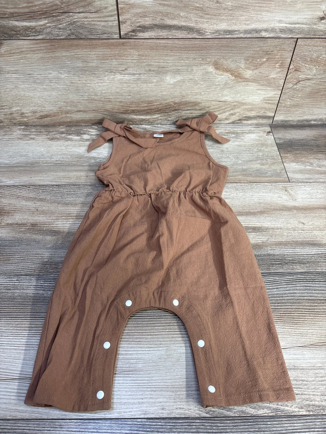 Flat lay of brown sleeveless baby jumpsuit with tied shoulder bows and snap-crotch closure on wood plank background