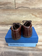 Rear view of Stride Rite SRTech Elliot sneakers, brown leather with white stitching, on blue shoebox on wood floor