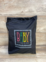 Front view of Baby Change-N-Go in black drawstring bag showcasing colorful BABY logo on wood floor