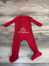 Red baby sleeper with 'my first christmas' text, footed, on wooden background