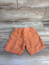 Flat lay of orange Cat & Jack toddler drawstring textured shorts with elastic waistband, back patch pocket on wood floor