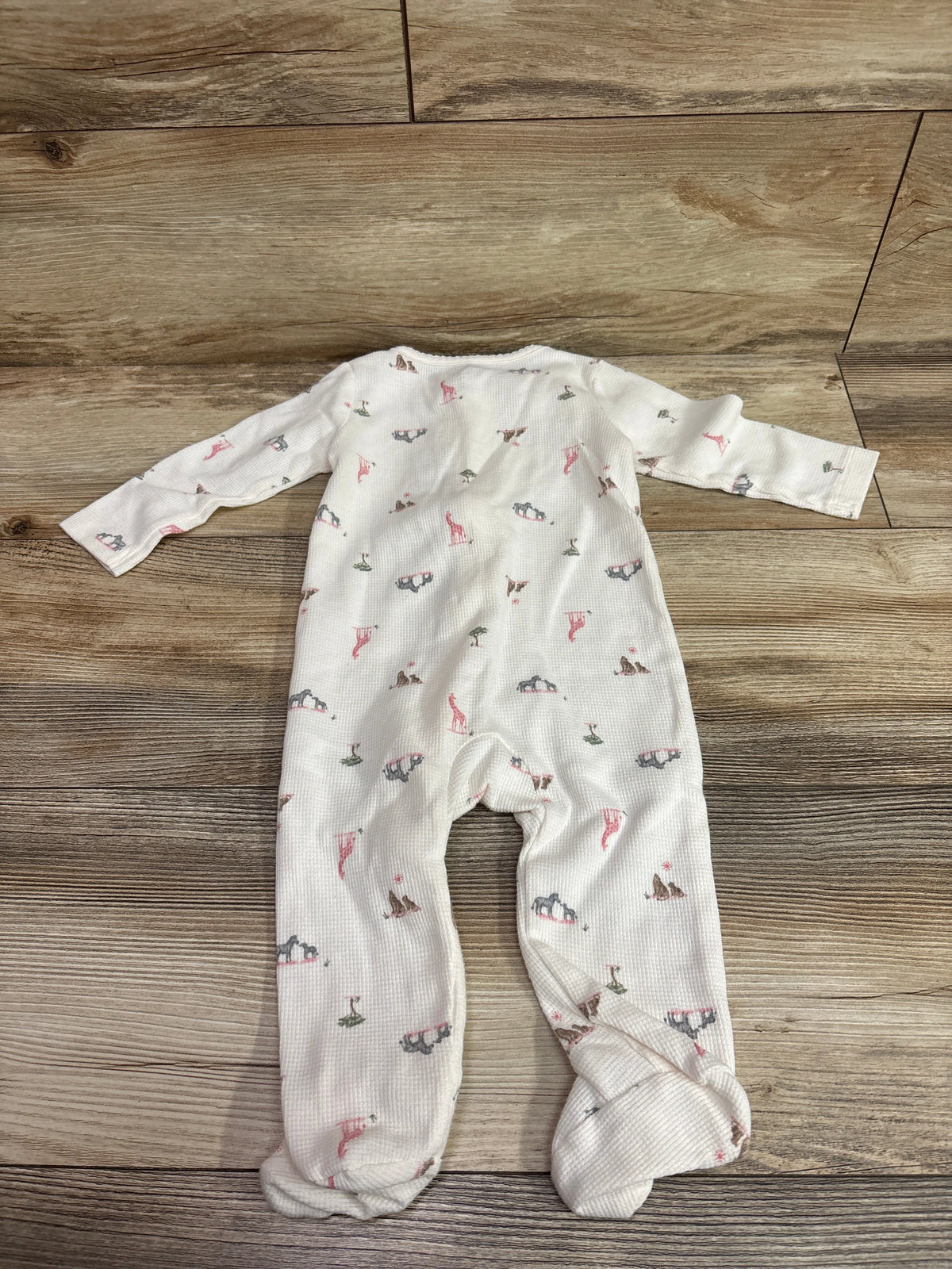 Top view of Just One You waffle knit sleeper, size 9 months, with long sleeves, footed legs, and animal print on wood flooring