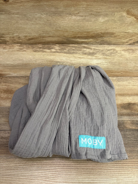 Top view of a gray Moby ring sling baby carrier showcasing its gathered fabric and Moby label on a wood surface