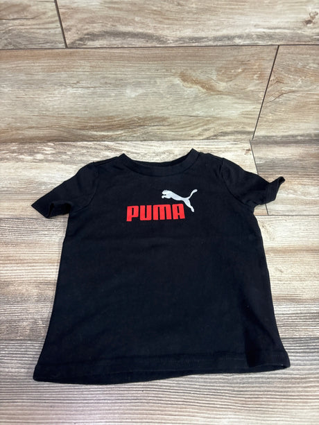 Black toddler t-shirt with a red and white Puma logo on a wooden background.