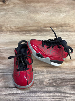 Red and grey toddler sneakers with black laces on a wood background