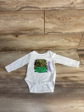 White baby onesie with green Frankenstein graphic and 'Delanie' text, laid on wood floor