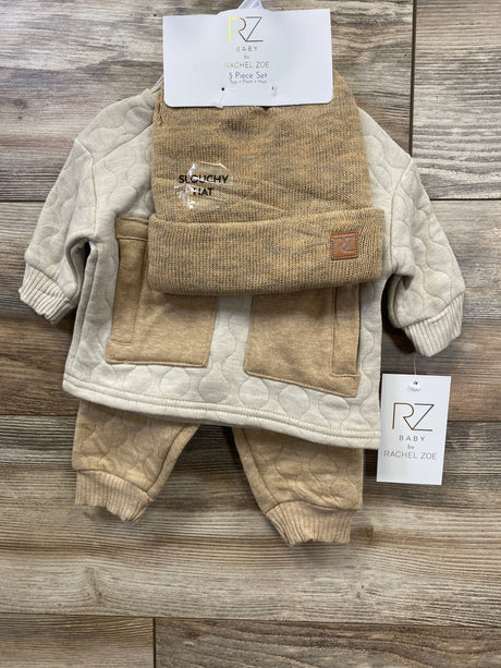 Neutral baby outfit set with quilted top, pants, and knit hat on wood background