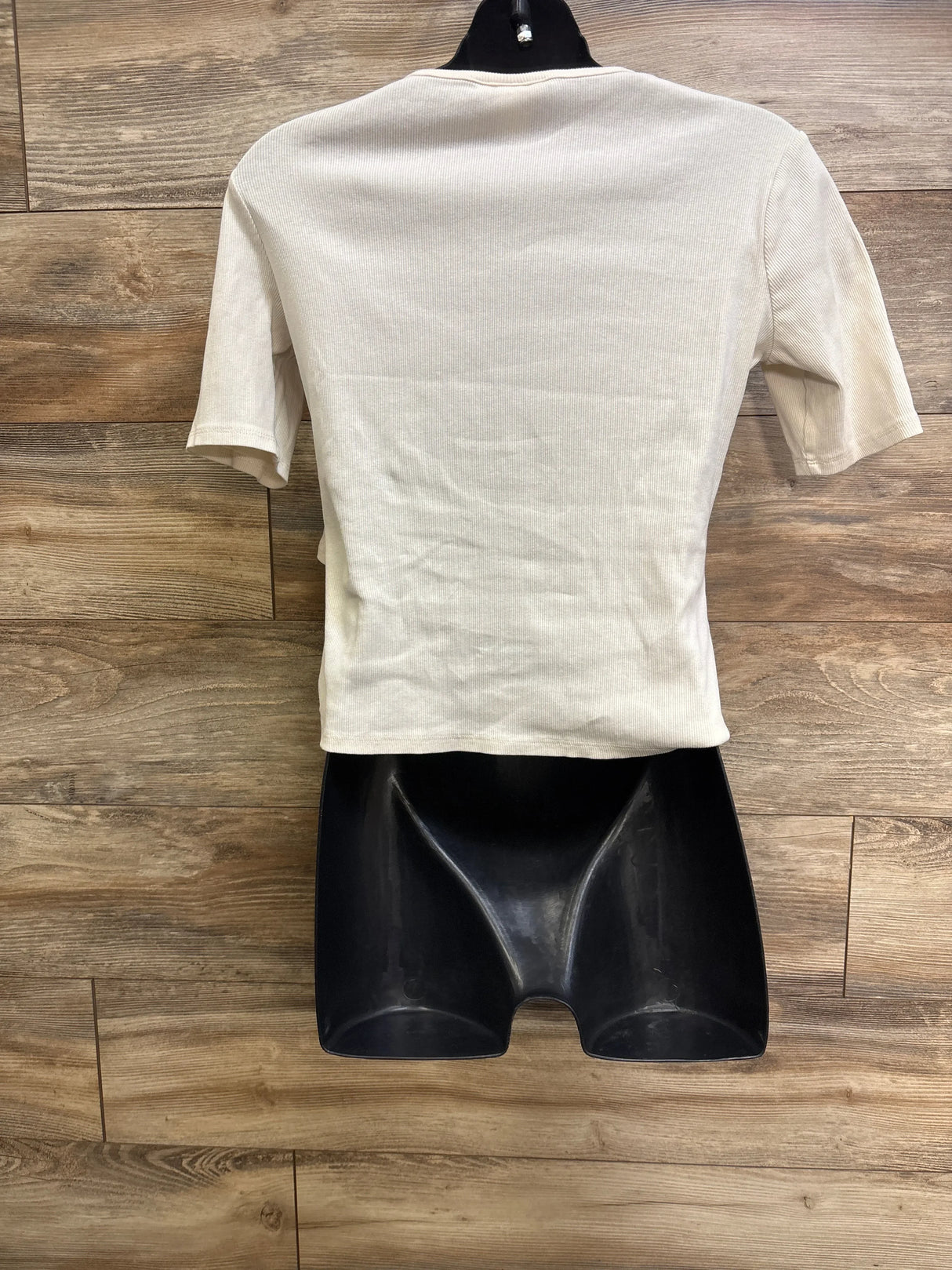 Back view of H and M Mama ribbed nursing shirt in ivory on black mannequin with wood background