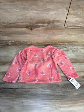 Pink toddler long sleeve shirt with white heart pattern on wood background