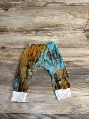 Tie dye baby pants with teal, brown, and white cuffs on wood background