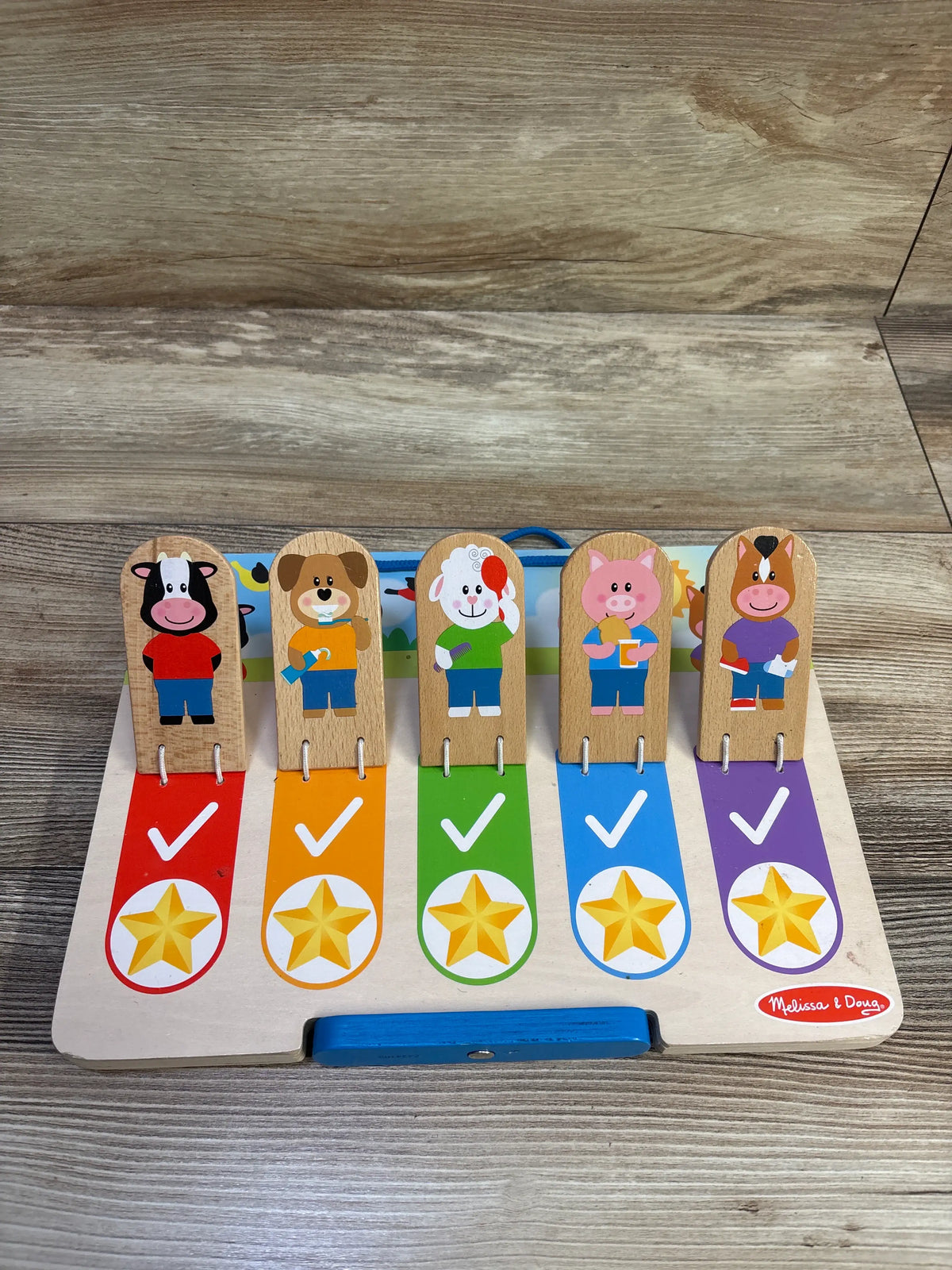 Front view of Melissa & Doug My Daily Day and Night Wooden Routines Chart showing five animal trackers and colored checkmarks