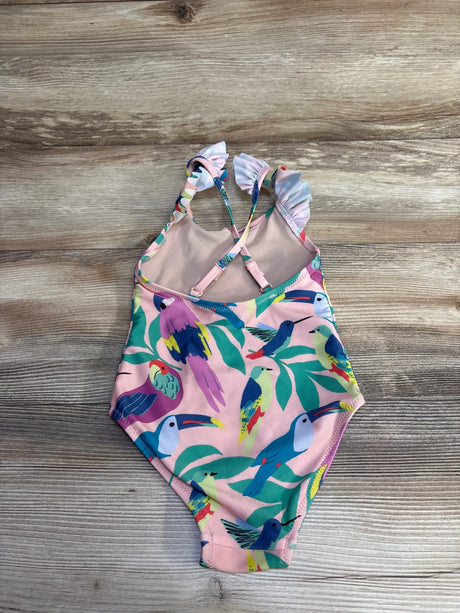 Flat lay of pink TEA one-piece swimsuit size 4T with ruffle straps and multicolored bird print on wood background