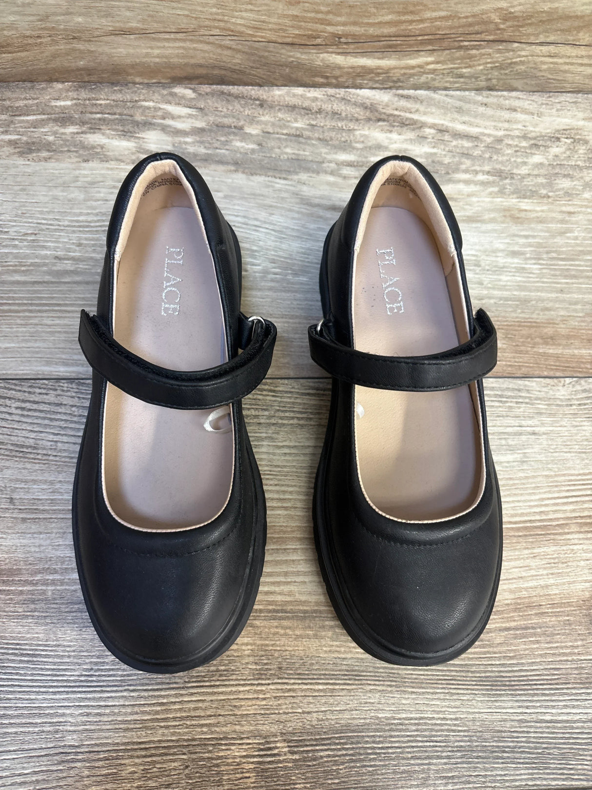 Black kids Mary Jane dress shoes with hook and loop strap on wood background