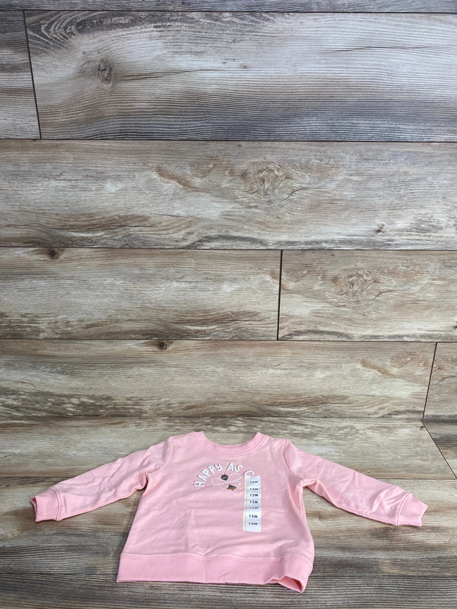 Pink long-sleeve toddler shirt with flower graphic and size 12M tag on rustic wood floor