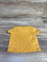 Back view of First Impressions yellow baby pocket shirt showing short sleeves and crew neckline on wood background