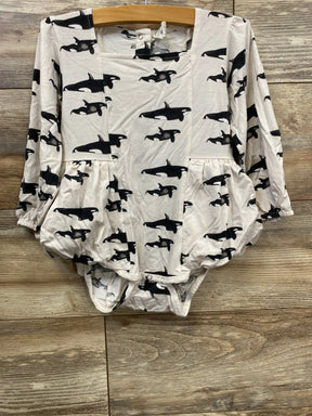 Long sleeve baby romper with black orca whale print on cream fabric, displayed on wood background