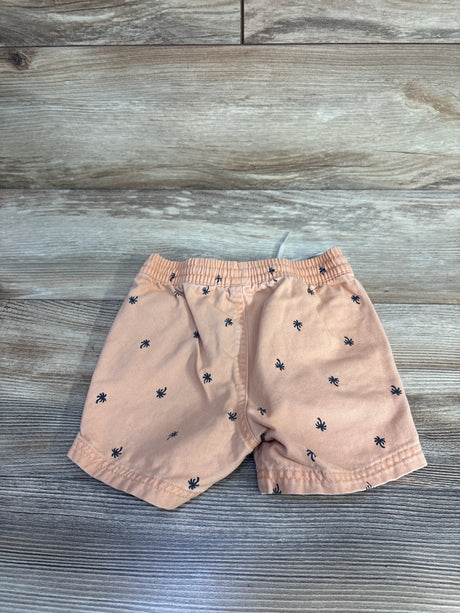 Front view of orange toddler twill shorts showcasing elastic waistband and navy palm tree print with wood plank background