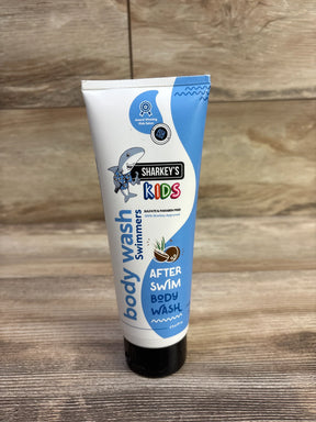 Front view of Sharkey's Kids After Swim body wash tube (6 oz) showing shark logo and blue and white packaging on wooden surface