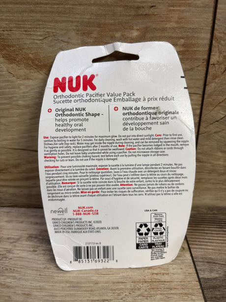 Back view of NEW NUK 3pk orthodontic pacifiers, mint green 0-6m, showing care instructions on wood