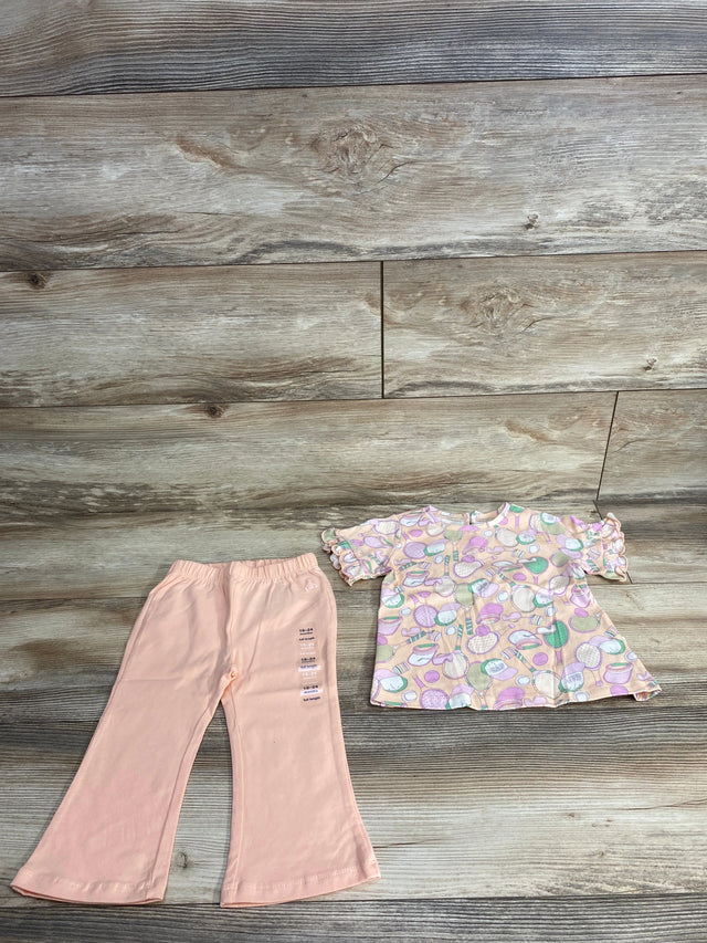 Toddlers peach bell-bottom pants with size label and pastel short-sleeve top with tennis racket pattern on wood floor