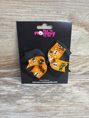 Halloween-themed hair bows with skulls and cats on orange ribbon, perfect for kids' festive outfits.