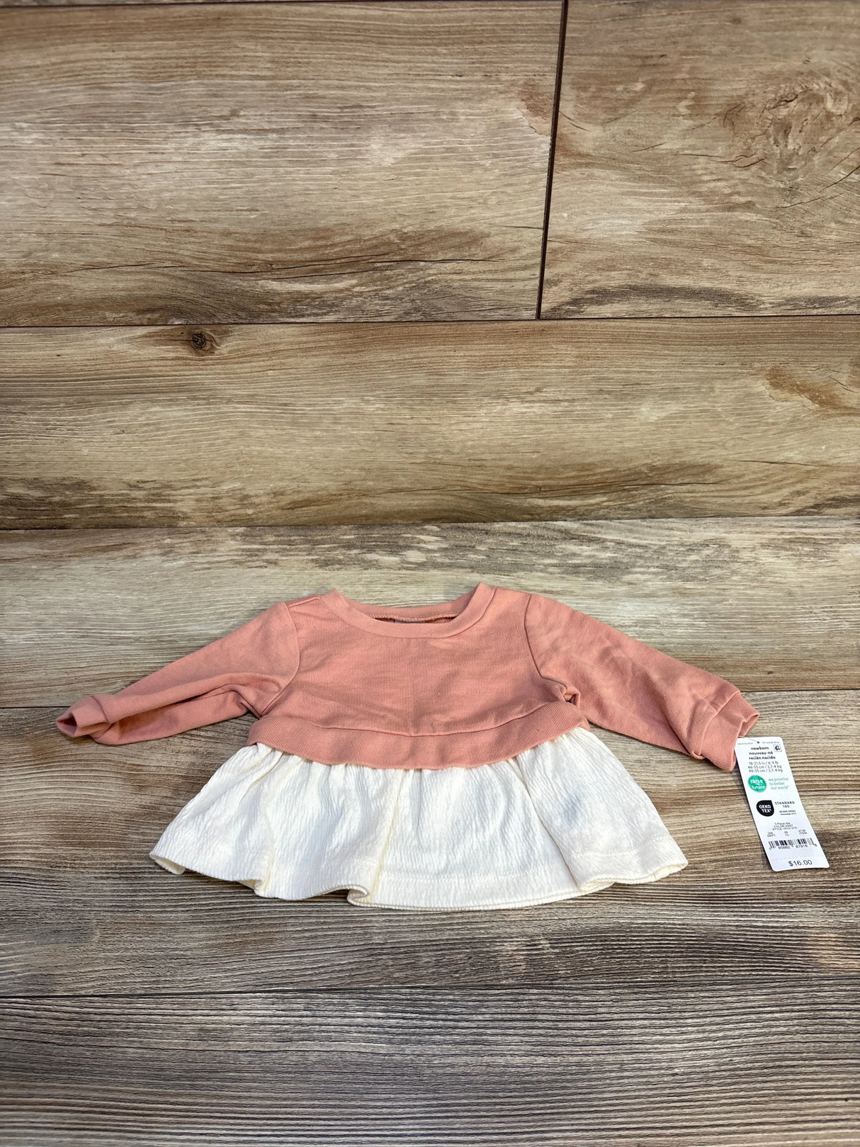 Baby girl long sleeve pink and white dress displayed on wood floor with price tag attached