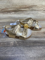 Gold toddler sandals with velcro straps and cork soles on wood background